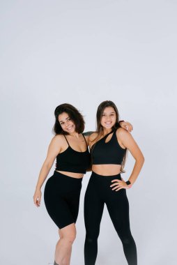 Beyaz arka planda poz veren iki genç kadın.