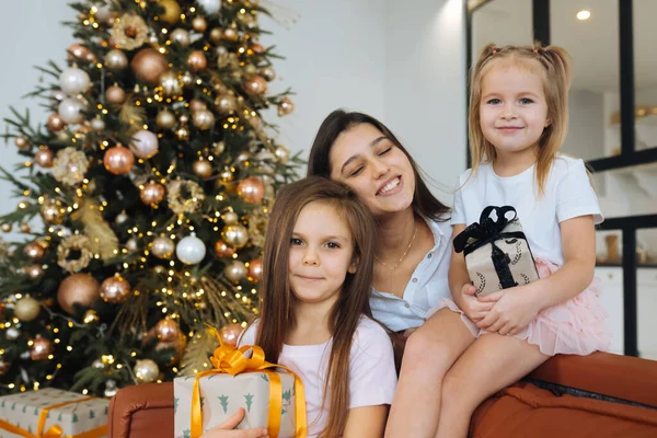 Ibu dan dua putri kecil dengan latar belakang pohon Natal — Stok Foto