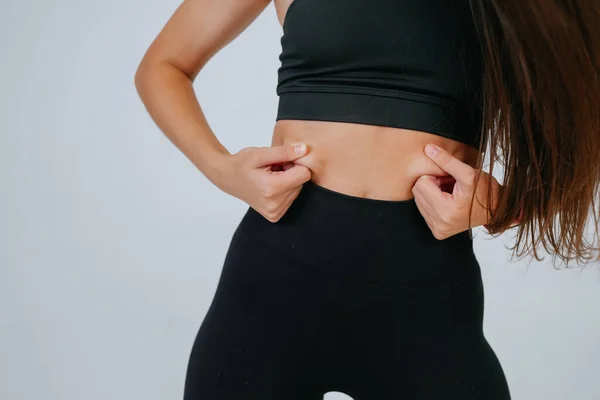 Mujer joven mostrando grasa en su vientre sobre fondo blanco. —  Fotos de Stock