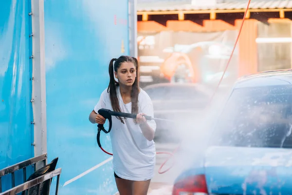 Bruna da un tubo ad alta pressione lava l'auto in un autolavaggio — Foto Stock