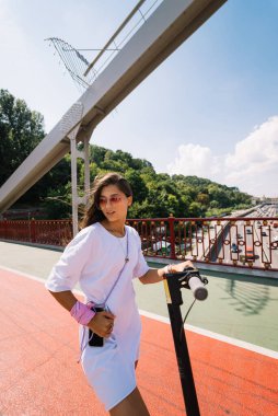 Genç, güzel bir kadın ve elektrikli scooter, ekolojik nakliye aracı.