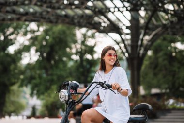 Genç, güzel bir kadın ve elektrikli scooter, ekolojik nakliye aracı.