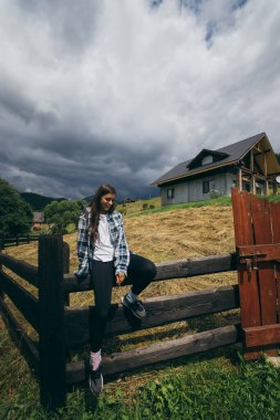 Çitin üzerinde oturan genç ve çekici beyaz bir kadın.