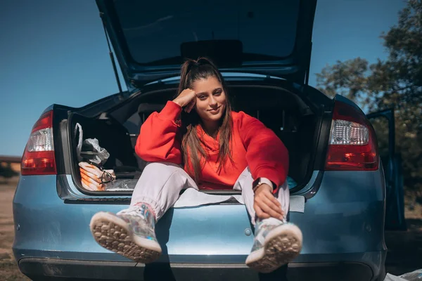 Jovem atraente descansando no porta-malas de um carro — Fotografia de Stock