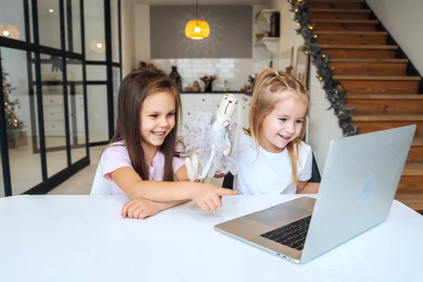 식탁에 앉아서 노트북에서 놀고 있는 두 어린 소녀 — 스톡 사진