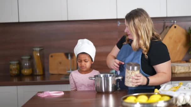 Ευτυχισμένη μαμά και κόρη κορίτσι διασκεδάζουν ενώ μαγειρεύουν στην κουζίνα. — Αρχείο Βίντεο