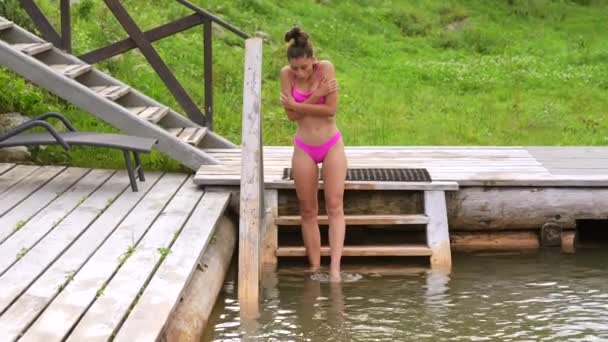 비키니를 입은 젊은 여자가 차가운 물 속으로 뛰어들다 — 비디오
