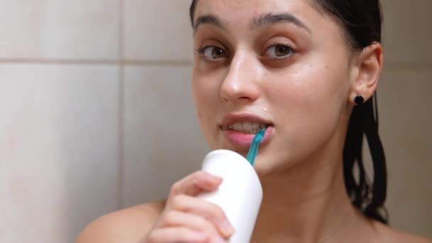 Smiling woman cleaning her teeth with oral irrigator. — Stock Video