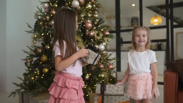 チャーミング小さな女の子はクリスマスツリーの背景に贈り物を保持しています — ストック動画