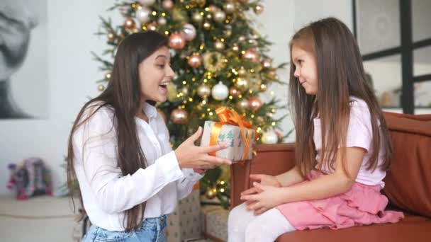 Joven madre calmándose y dando un regalo a su hija — Vídeo de stock