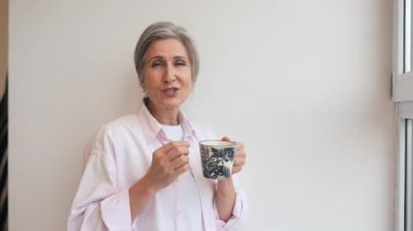 Rastgele giyinmiş yaşlı bir kadının portresi. Elinde bir kupa var.