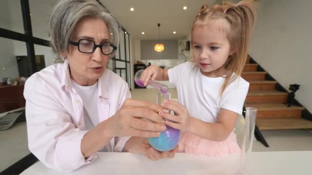 Attentive old grandma assist grandkid in funny scientific experiments — Stock Video