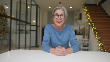 Gözlüklü, kameraya bakan yaşlı bir kadının portresi.