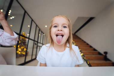 Küçük kız kameranın önünde dilini dışarı çıkarıyor.