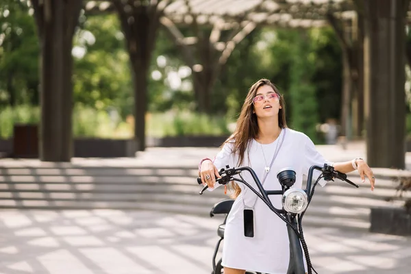 Молодая красивая женщина и электрический скутер, экологический транспорт — стоковое фото