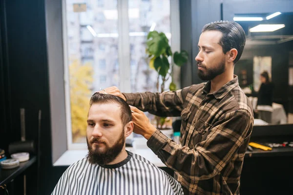Веселый молодой бородатый мужчина стрижется в парикмахерской — стоковое фото
