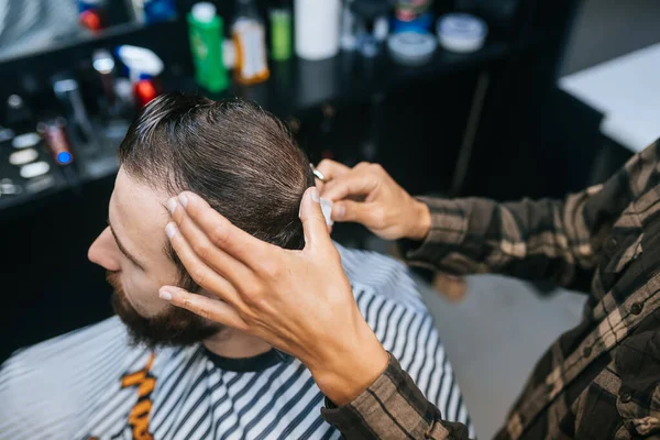 Alegre joven barbudo conseguir corte de pelo por peluquería en la barbería — Foto de Stock