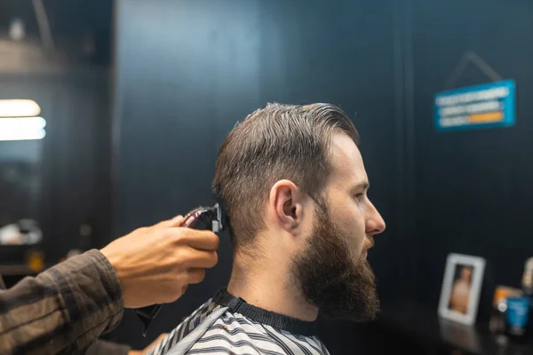 Mestre em barbearia faz homens corte de cabelo com cortador de cabelo — Fotografia de Stock