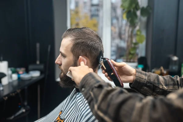 Mestre em barbearia faz homens corte de cabelo com cortador de cabelo — Fotografia de Stock