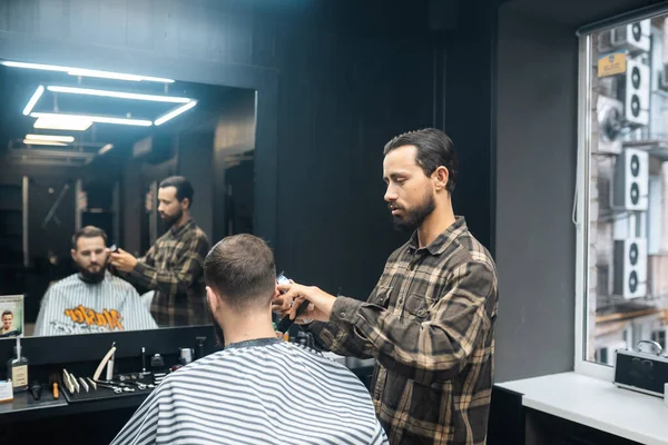 Mestre em barbearia faz homens corte de cabelo com cortador de cabelo — Fotografia de Stock