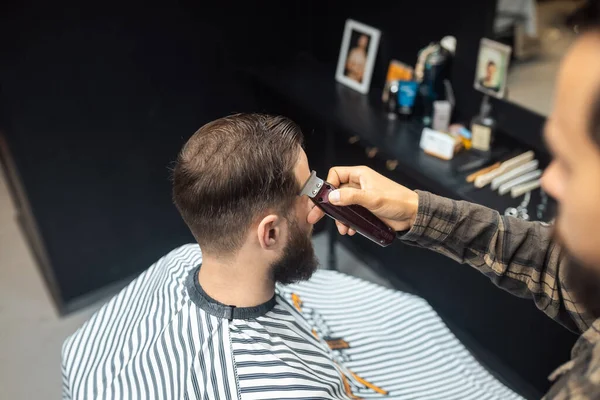 Maestro en barbería hace mens corte de pelo con cortador de pelo — Foto de Stock