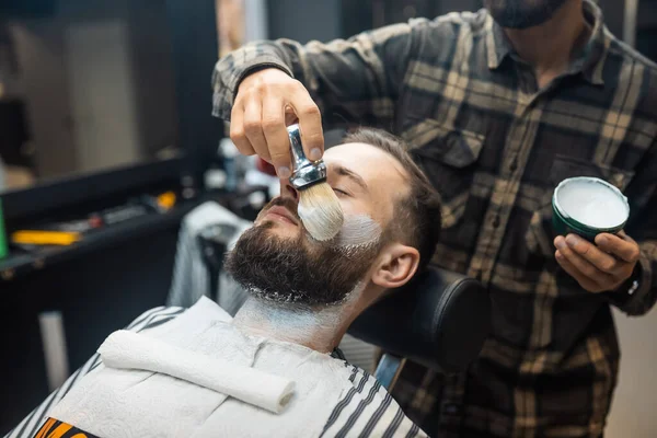 Master εφαρμόζοντας αφρό ξυρίσματος στο πρόσωπο του πελάτη — Φωτογραφία Αρχείου
