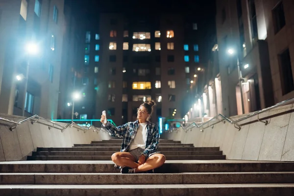 Женщина разговаривает по видеосвязи в ночном городе — стоковое фото