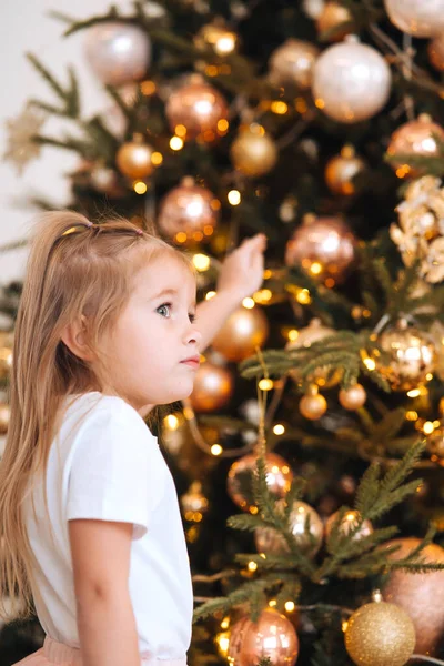 Charmantes kleines Mädchen auf einem Hintergrund von Weihnachtsbäumen — Stockfoto