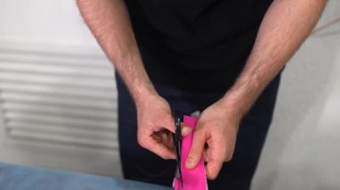Fizyoterapist hazırlar ve kinesio taping keser.