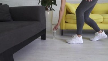 Spor kıyafetli genç bir kadın şişeden su içiyor.