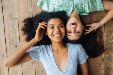 İki genç kadın kafa kafaya yerde yatıyor.