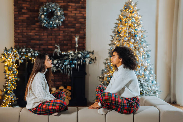 Two female student friends sitting on the couch at home. Stock Picture