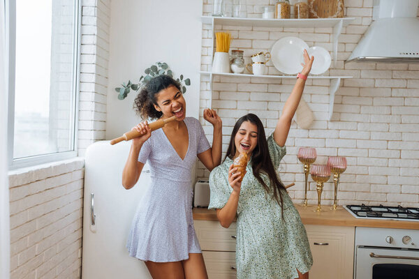 Two girls of different races having fun in the kitchen Stock Picture