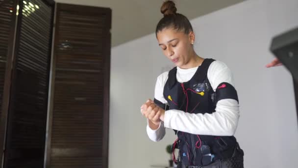 Treinamento EMS. Menina fazendo exercícios em um terno com cabos. — Vídeo de Stock