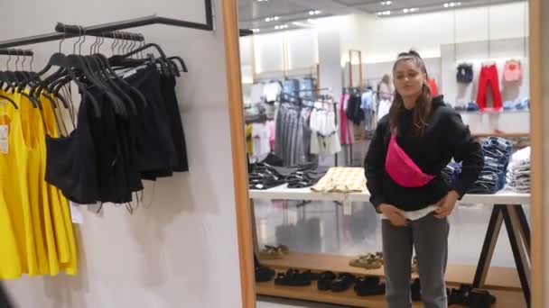 Pretty young woman shopping in clothes store — Stock Video