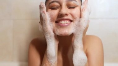 Yakın çekim neşeli kadın hafif banyoda köpükle oynuyor.
