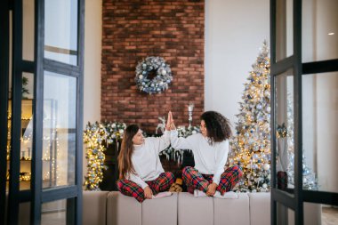 Evdeki kanepede oturan iki kız öğrenci arkadaş. Çak.