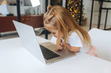 Tablet bilgisayar kullanan küçük kız masada oturuyor.