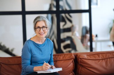 Gözlüklü mutlu son sınıf öğrencisi. Evdeki deftere yazıyor.