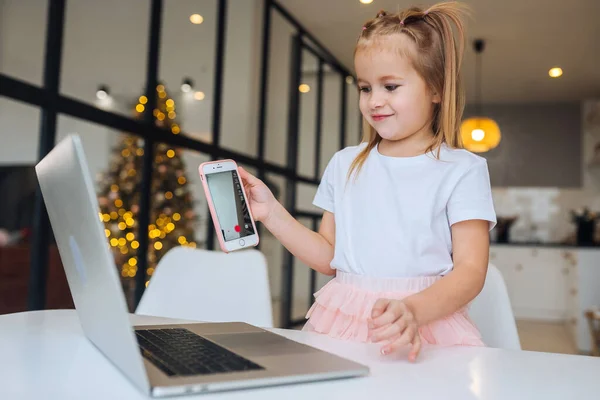 小さな子供は机に座ってノートパソコンの携帯電話を持って — ストック写真