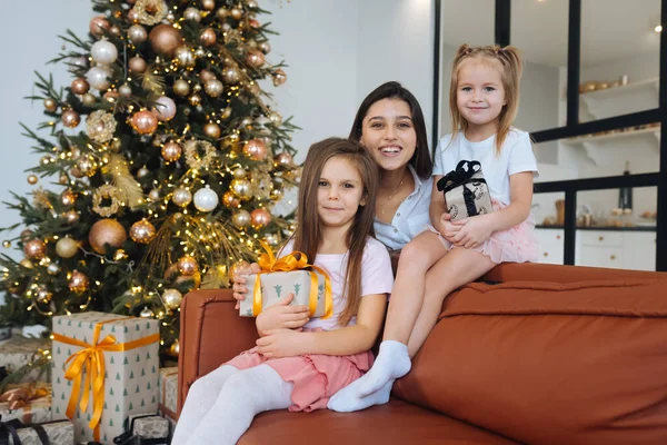 แม่และลูกสาวสองคนกับพื้นหลังของต้นคริสต์มาส — ภาพถ่ายสต็อก