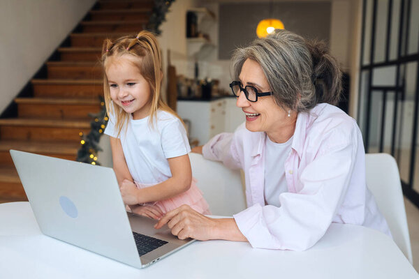 Child and granny looking at the camera with laptop Stock Picture