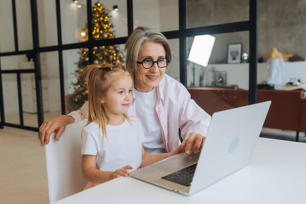 Child and granny looking at the camera with laptop Stock Image