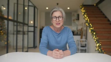 Gözlüklü, kameraya bakan yaşlı bir kadının portresi.