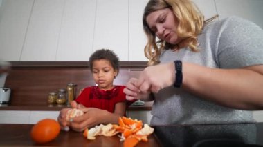 Mutlu anne ve kız mutfakta yemek pişirirken eğleniyorlar. Etnik ve ırksal olarak karışık bir aile.