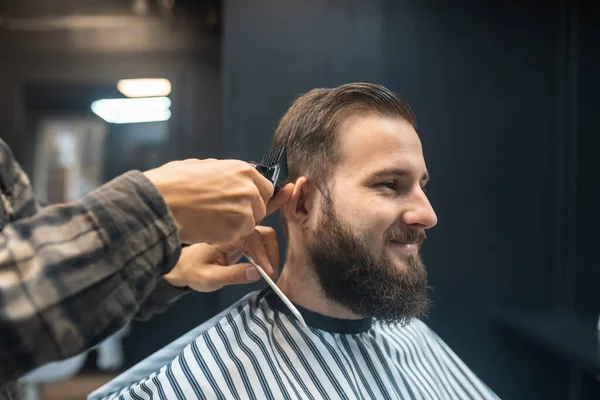 Mens hairstyling and haircutting with hair clipper in a barber shop or hair salon