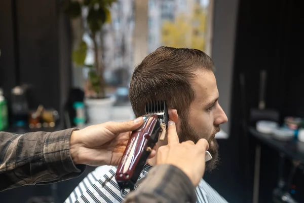 Mens hairstyling and haircutting with hair clipper in a barber shop or hair salon