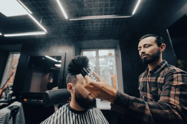 The master removes the remaining hair with a brush from the client while sitting in chair at barbershop. Time for new haircut.