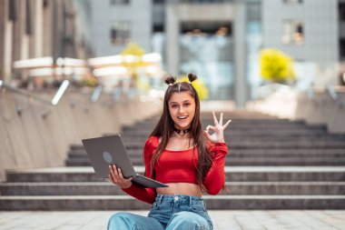 Sokaktaki güzel genç kadın ve bilgisayar laptopu kullanarak çalışıyor.