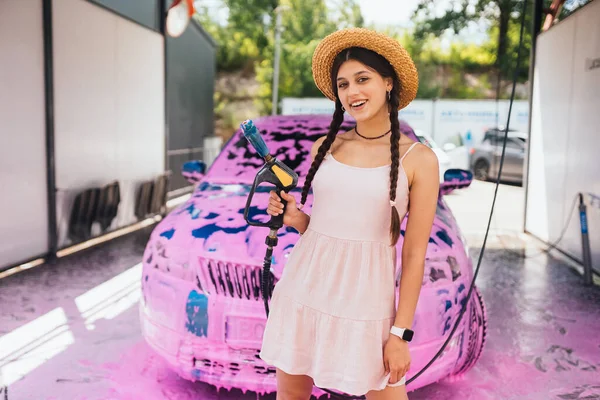 Young Woman High Pressure Hose Stands Front Car Covered Pink — 图库照片